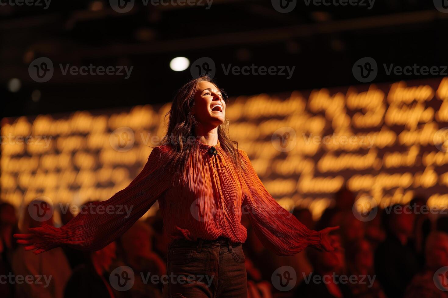 Performer expresses joy and energy on stage in front of an engaged audience during a nighttime event photo