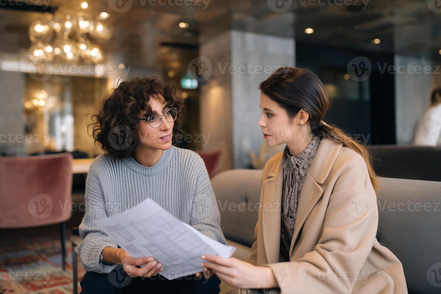 Two professionals discuss plans in a modern office lobby during a business meeting in the afternoon photo