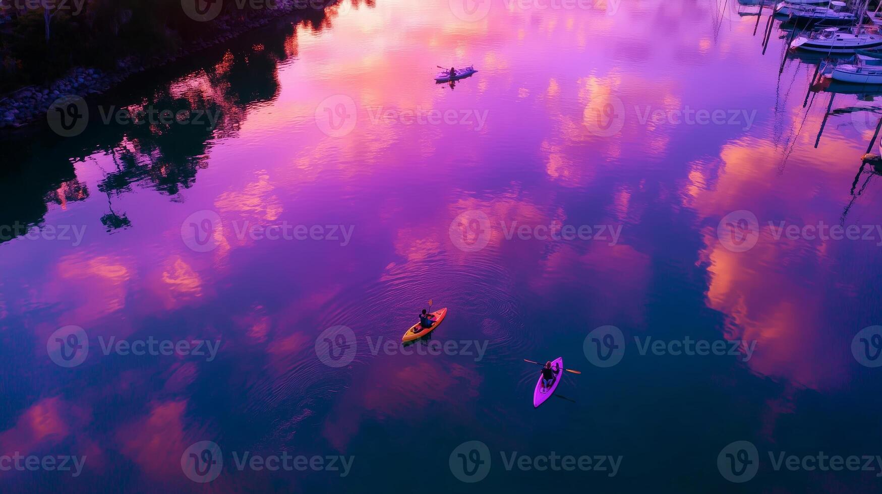 Kayakers enjoy a serene sunset paddle on a tranquil lake with vibrant pink and purple reflections photo