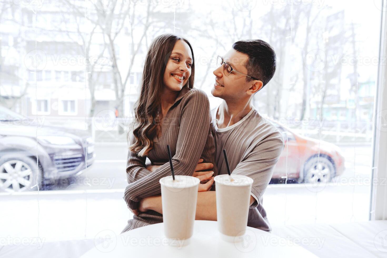 Young couple enjoying cozy time together in a cafe on a winter day while sipping warm beverages and smiling at each other photo