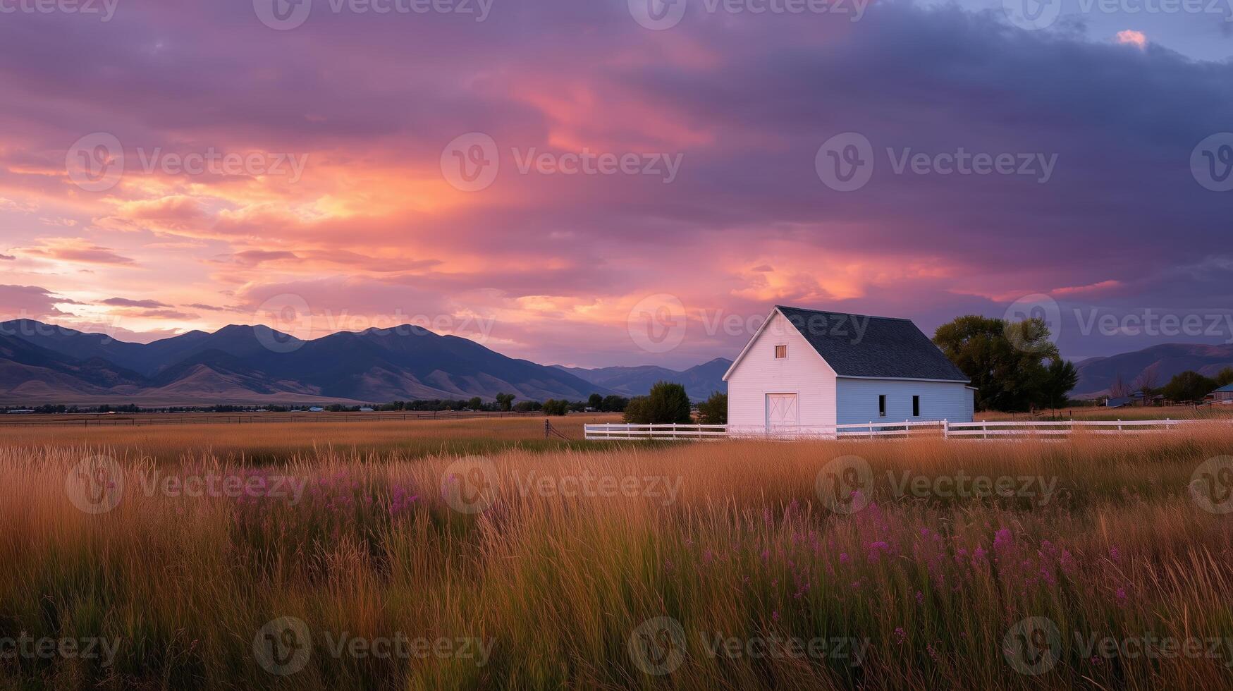 Sunset over a white barn in a colorful sky with mountains and fields in the foreground photo