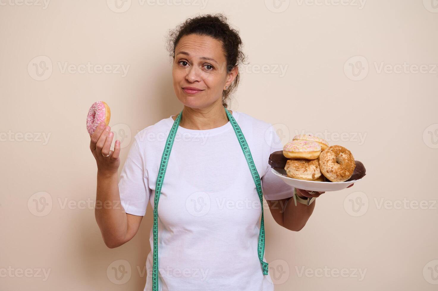 Woman Contrasting Doughnuts and Health Choices With Measuring Tape photo