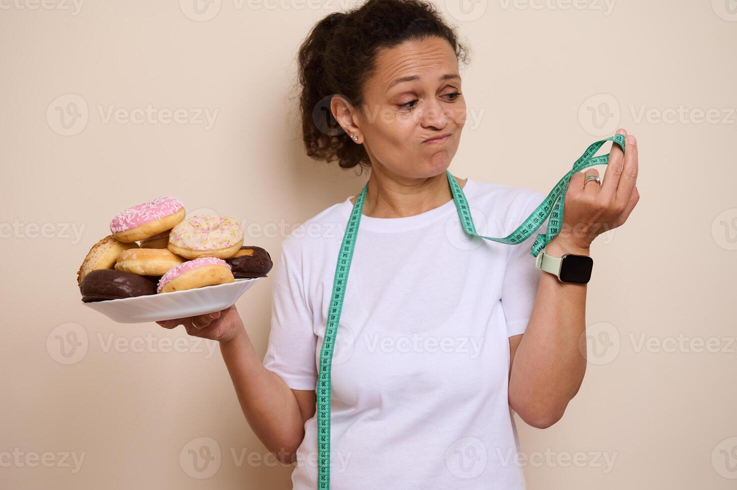 Woman Contemplating Donuts While Holding a Measuring Tape in a Health and Wellness Concept photo