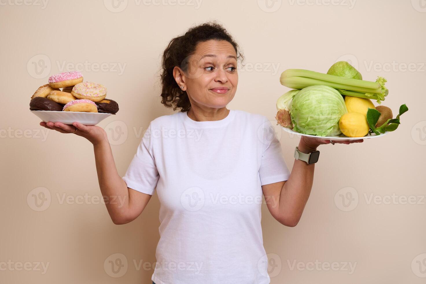 Woman Balancing Plates of Sweet Doughnuts and Healthy Fresh Vegetables in Thoughtful Decision photo