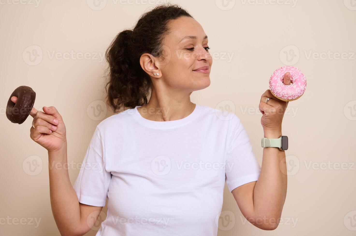 Smiling Woman Holding a Pink-Iced and Chocolate Doughnut in a Playful Pose, Highlighting Choices and Indulgence photo