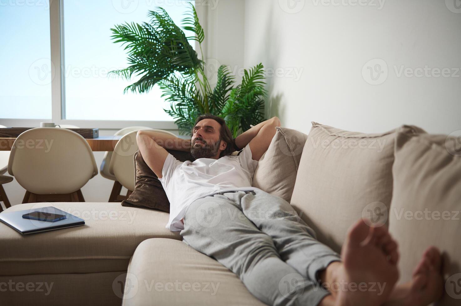 Man Relaxing on a Comfortable Couch in a Cozy Minimalist Living Room Setting photo