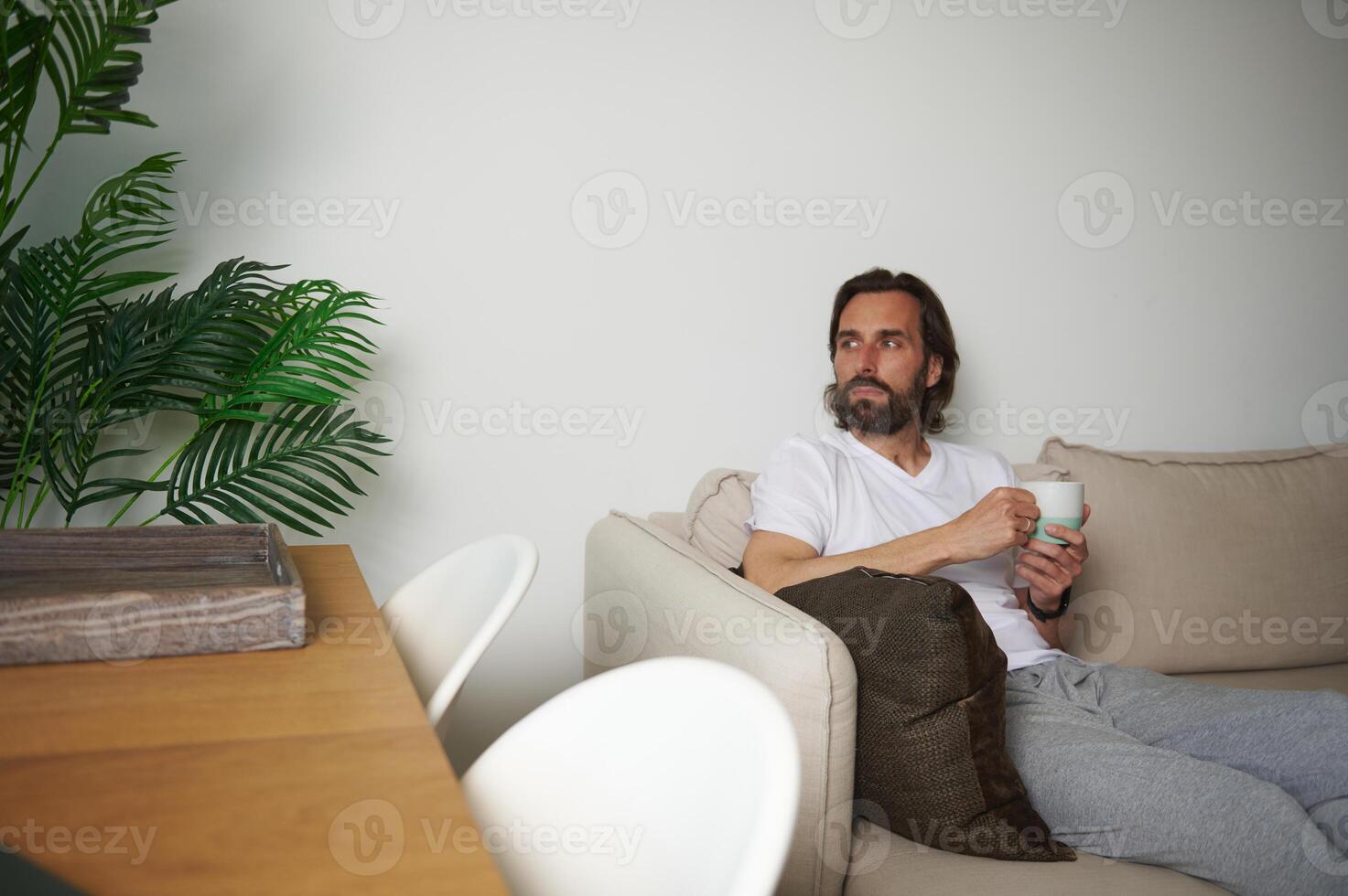 Man Relaxing on Sofa with Coffee in Cozy Minimalist Home Setting photo