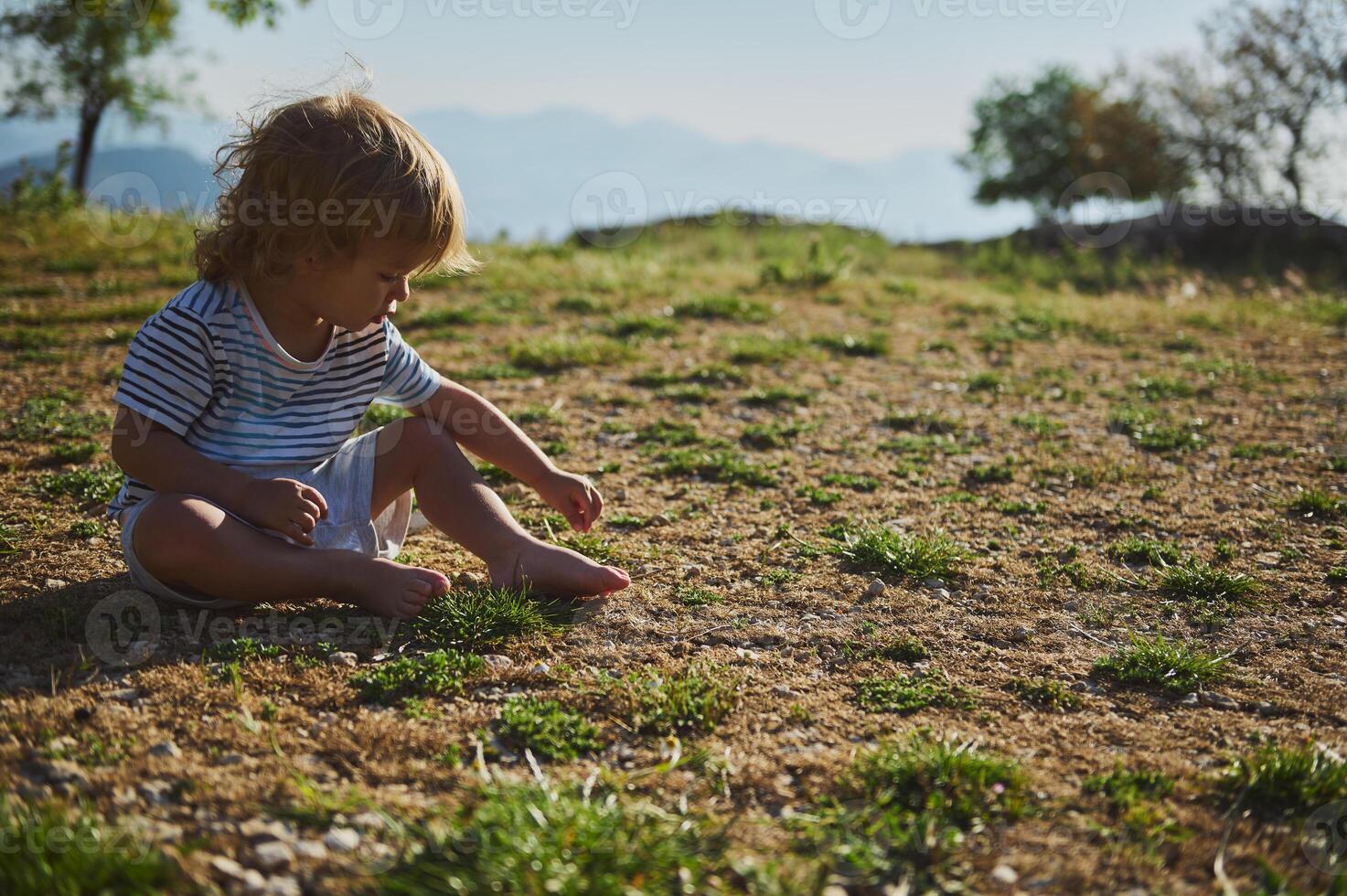 Child Sitting Outdoors in a Field Exploring Nature photo