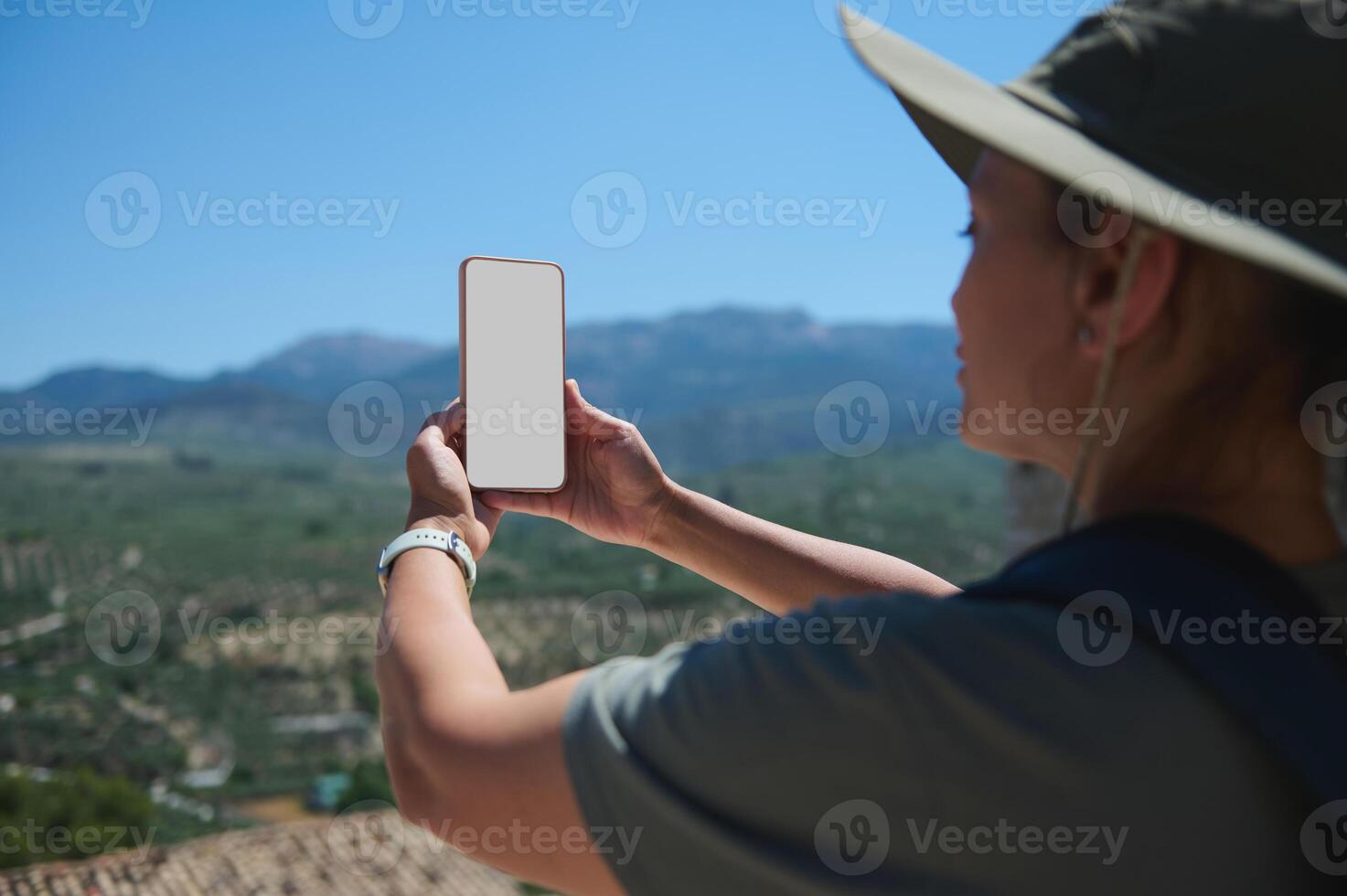 Traveler Exploring Scenic Landscape Using Smartphone with Blank Screen in Vibrant Mountain Setting photo