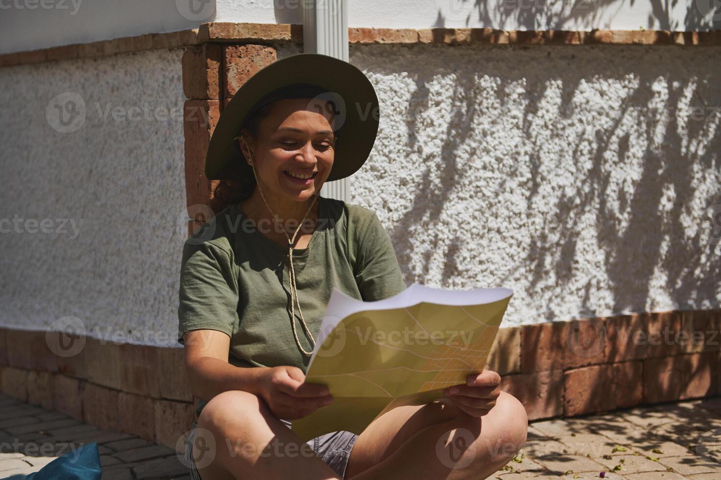 Smiling Traveler Reading a Map Outdoors in the Sun photo