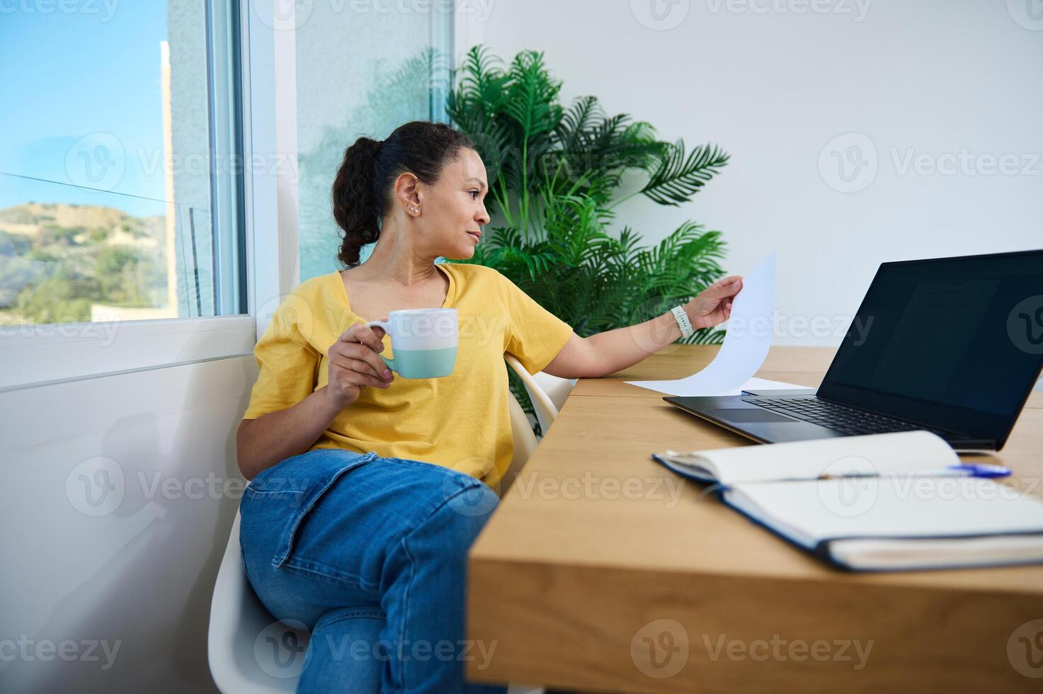 Businesswoman Reviewing Documents While Enjoying Coffee in Home Office photo