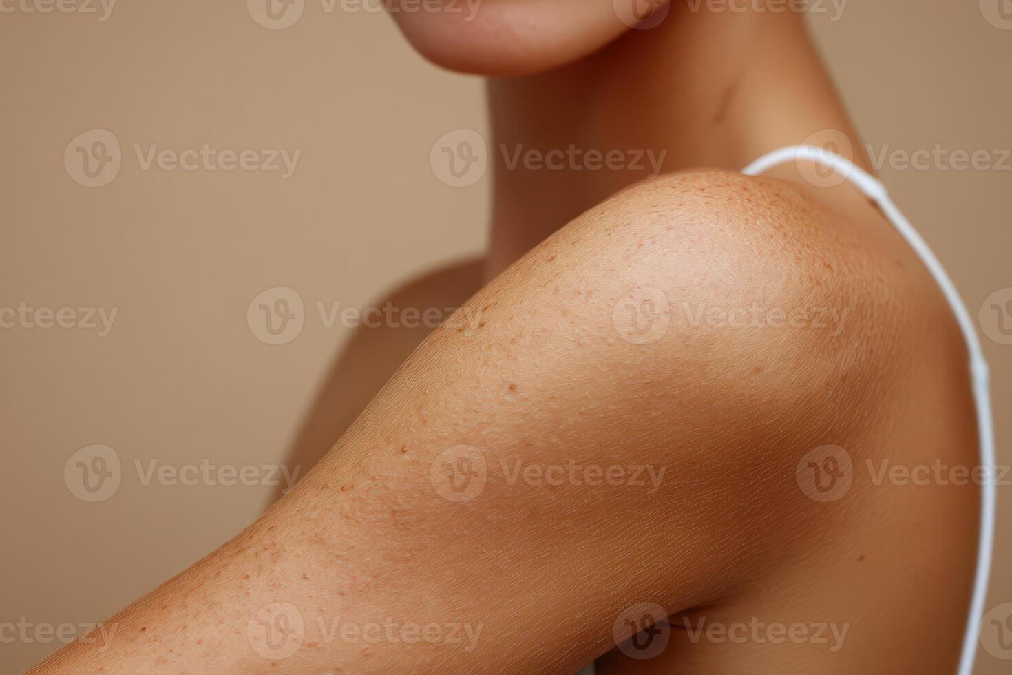 Close-up view of a woman's shoulder and collarbone area against a warm backdrop photo