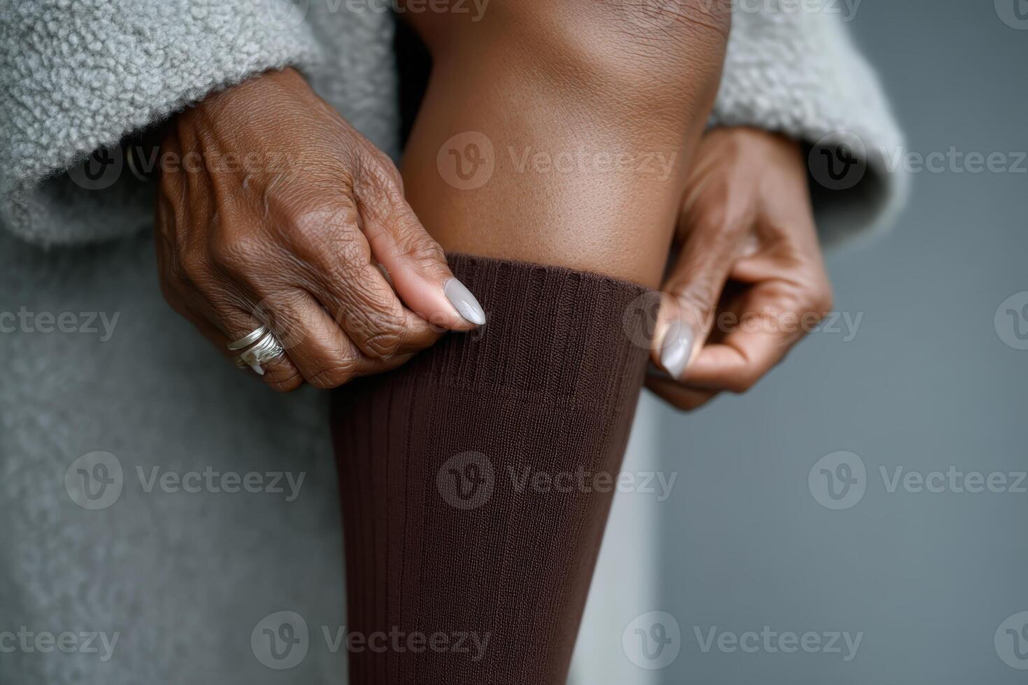 Woman adjusting brown knee-high socks in a cozy indoor setting during daytime photo