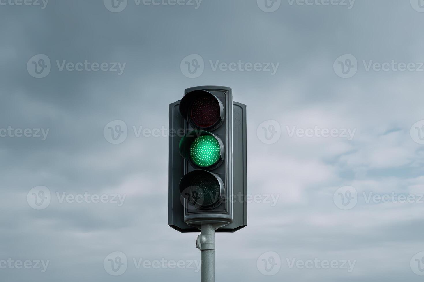 Green traffic light signals vehicles to proceed during overcast weather photo