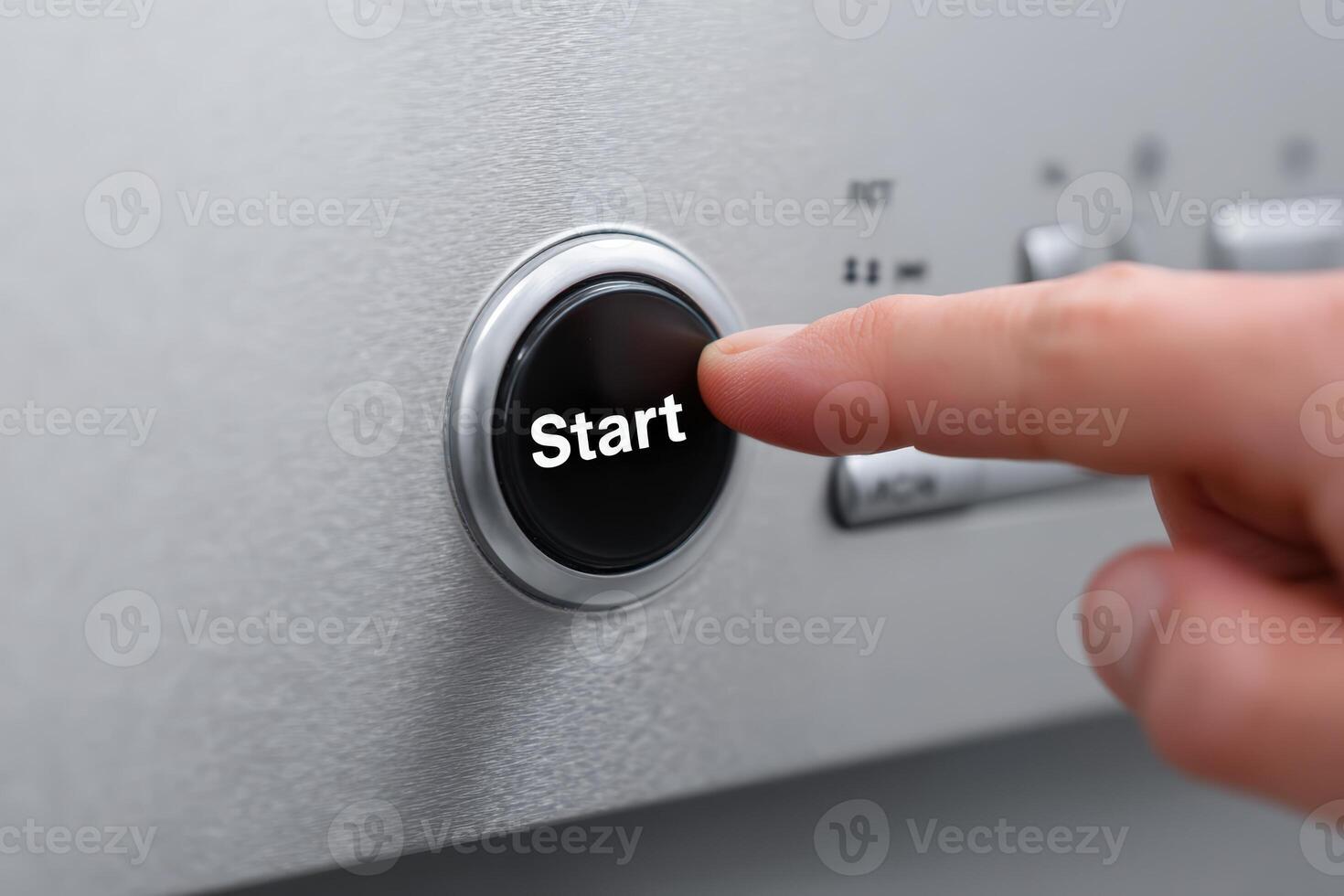 Person pressing start button on modern appliance in a kitchen setting during daytime photo