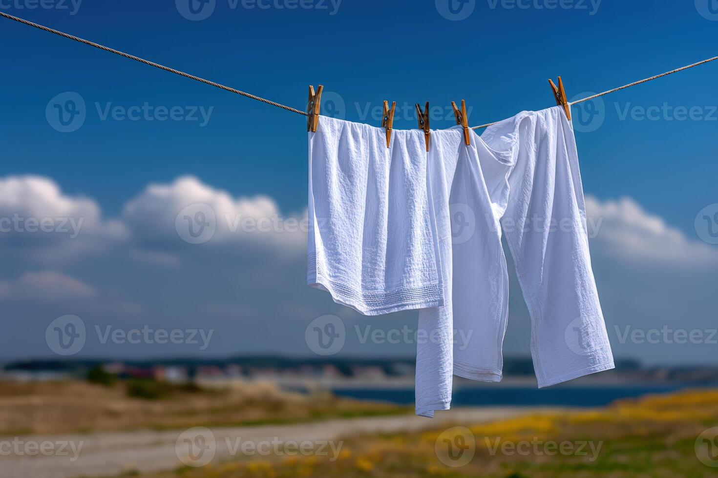 Freshly cleaned white clothes hung to dry in a serene outdoor setting near a body of water photo