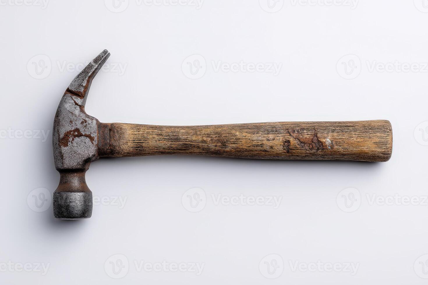 Chipped wooden handle hammer placed on a plain surface in a workshop setting photo
