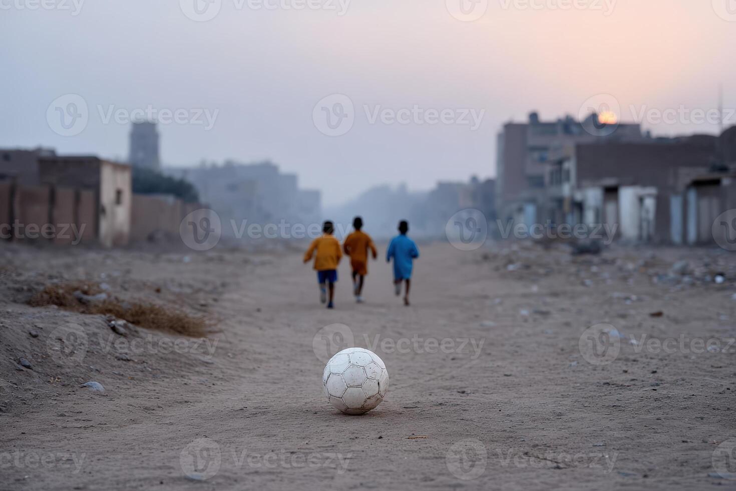 Children play soccer on a dusty street in a Middle Eastern town during sunset photo