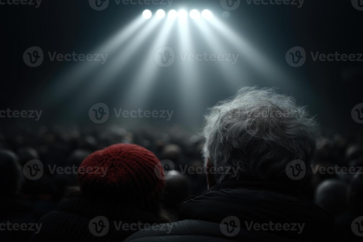 Audience members seated quietly as stage lights illuminate the theater photo