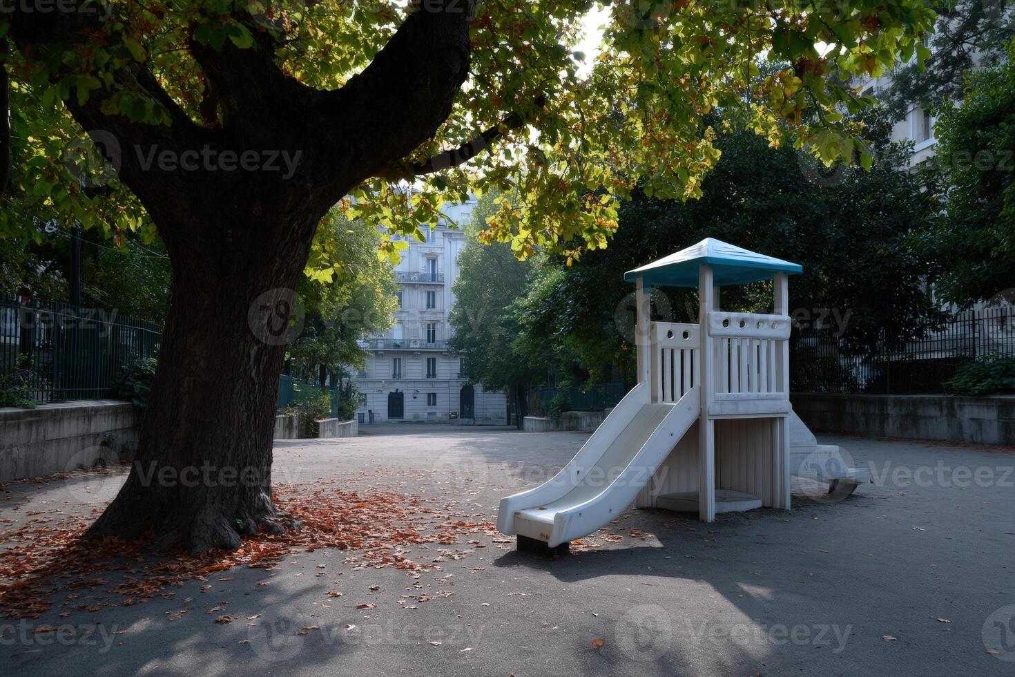 Miniature urban playground featuring a slide and surrounded by large trees in an empty area photo