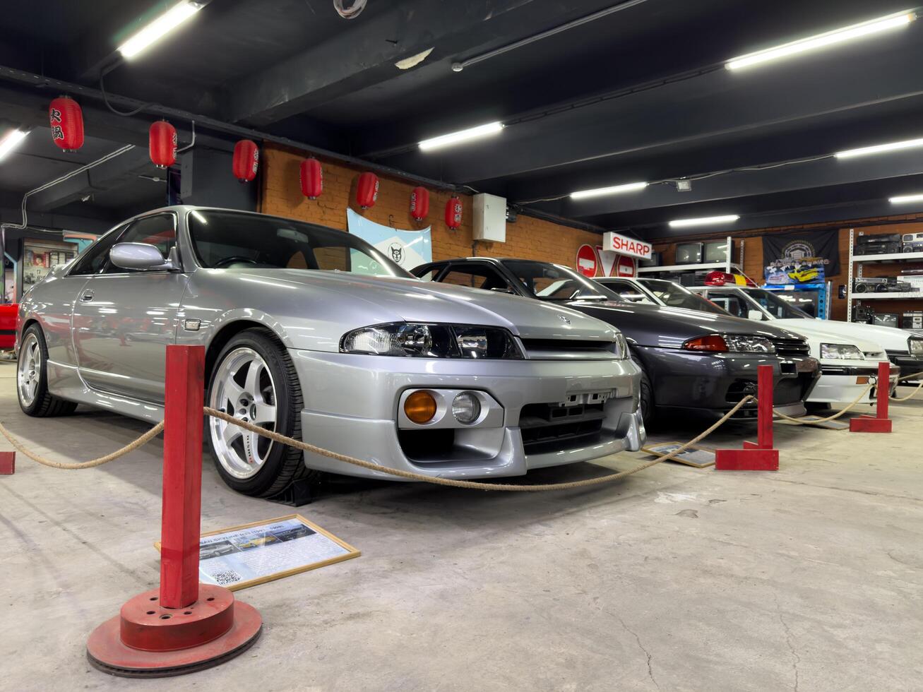 Moscow, Russia, April 27, 2025 Lineup of legendary Nissan Skyline GT-R models including the silver R33 and dark R32 on display at a Japanese car museum surrounded by retro electronics and decor photo