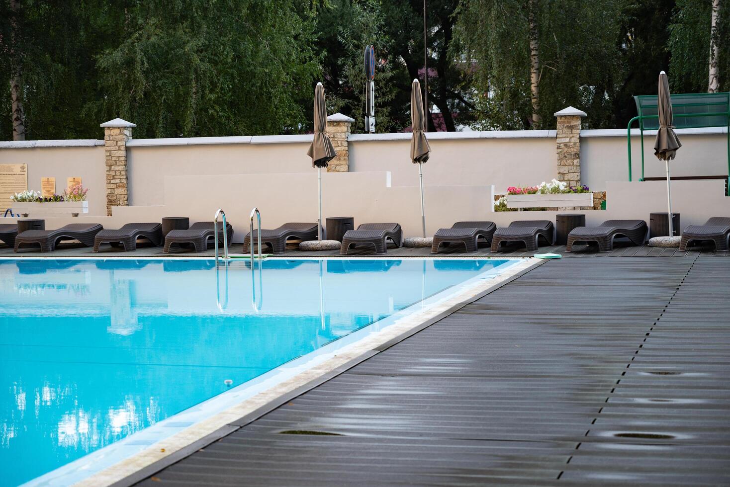swimming pool with metal ladder and lounge chairs around. photo
