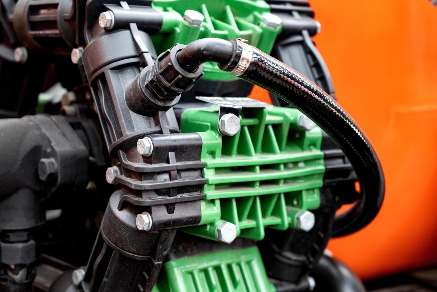 Close-up of industrial pump with green and black components, orange background. photo