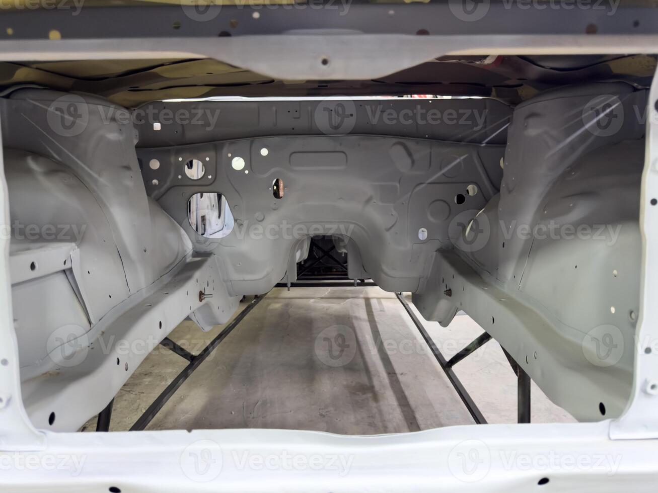 Symmetrical view of freshly primed car engine bay with detailed metalwork and structural panels, captured during a vehicle restoration process in professional workshop environment photo