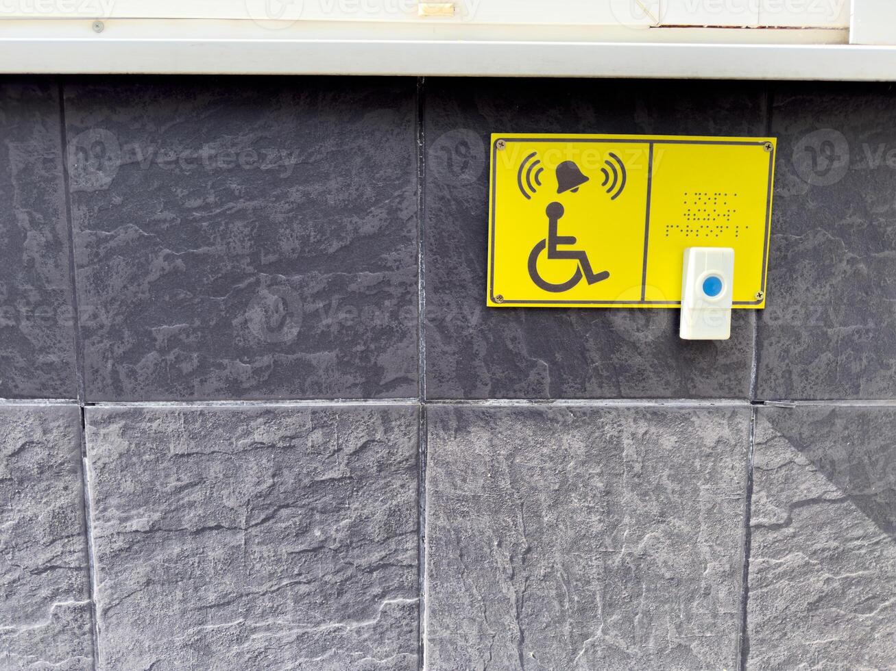 Accessible call button and Braille sign for wheelchair users on textured wall, symbolizing inclusive urban infrastructure and assistance for people with disabilities in public spaces photo