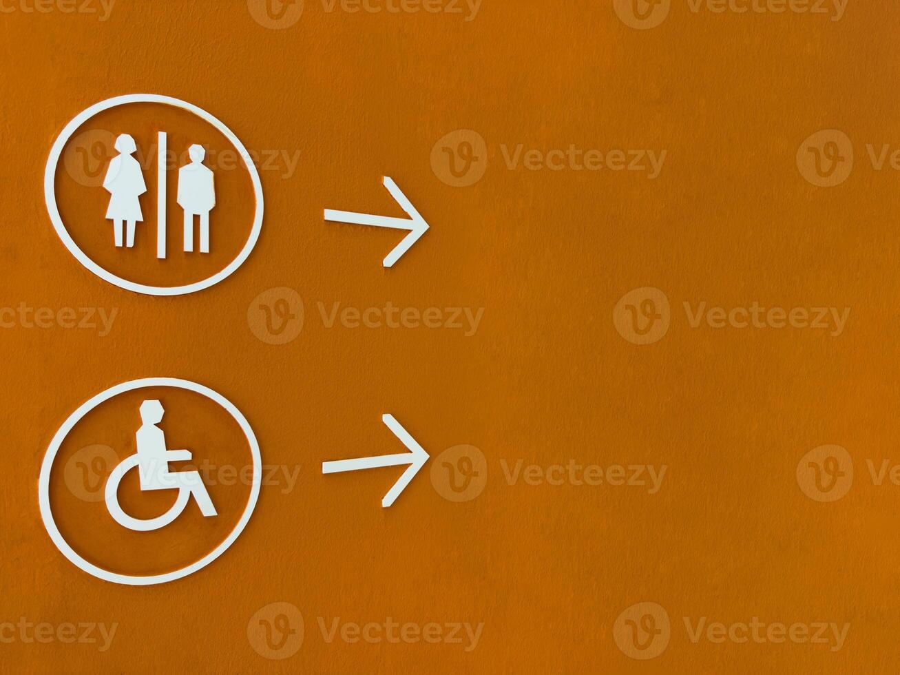 Modern restroom direction sign with male, female and wheelchair symbols on bold orange wall, pointing to the right. Accessible and inclusive design for public facilities navigation photo