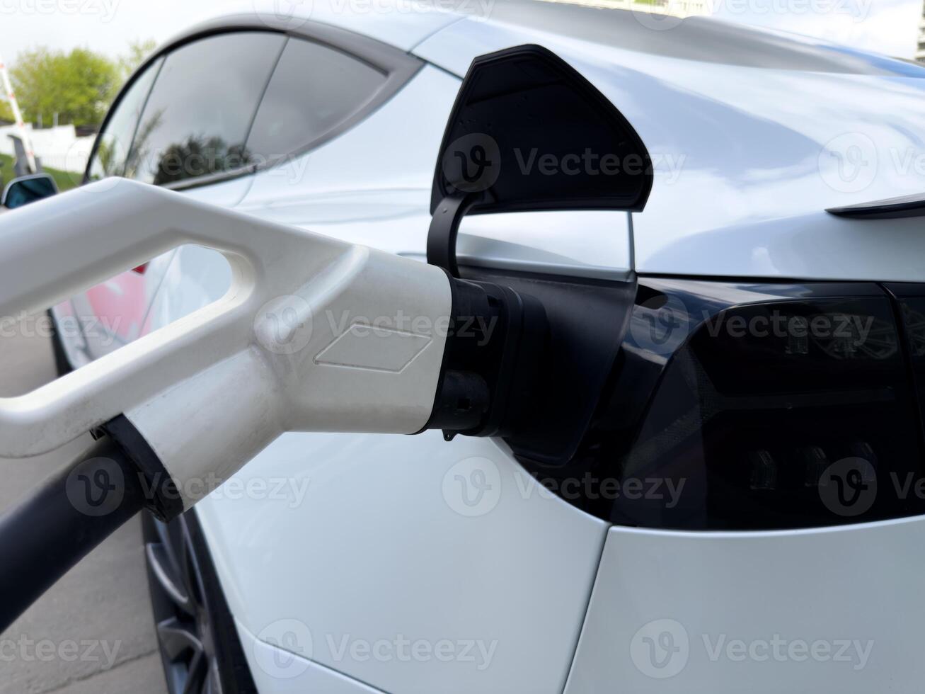 Close up of electric car being charged, highlighting the smooth aerodynamic curves and glossy surface, emphasizing premium design and future oriented automotive aesthetics photo
