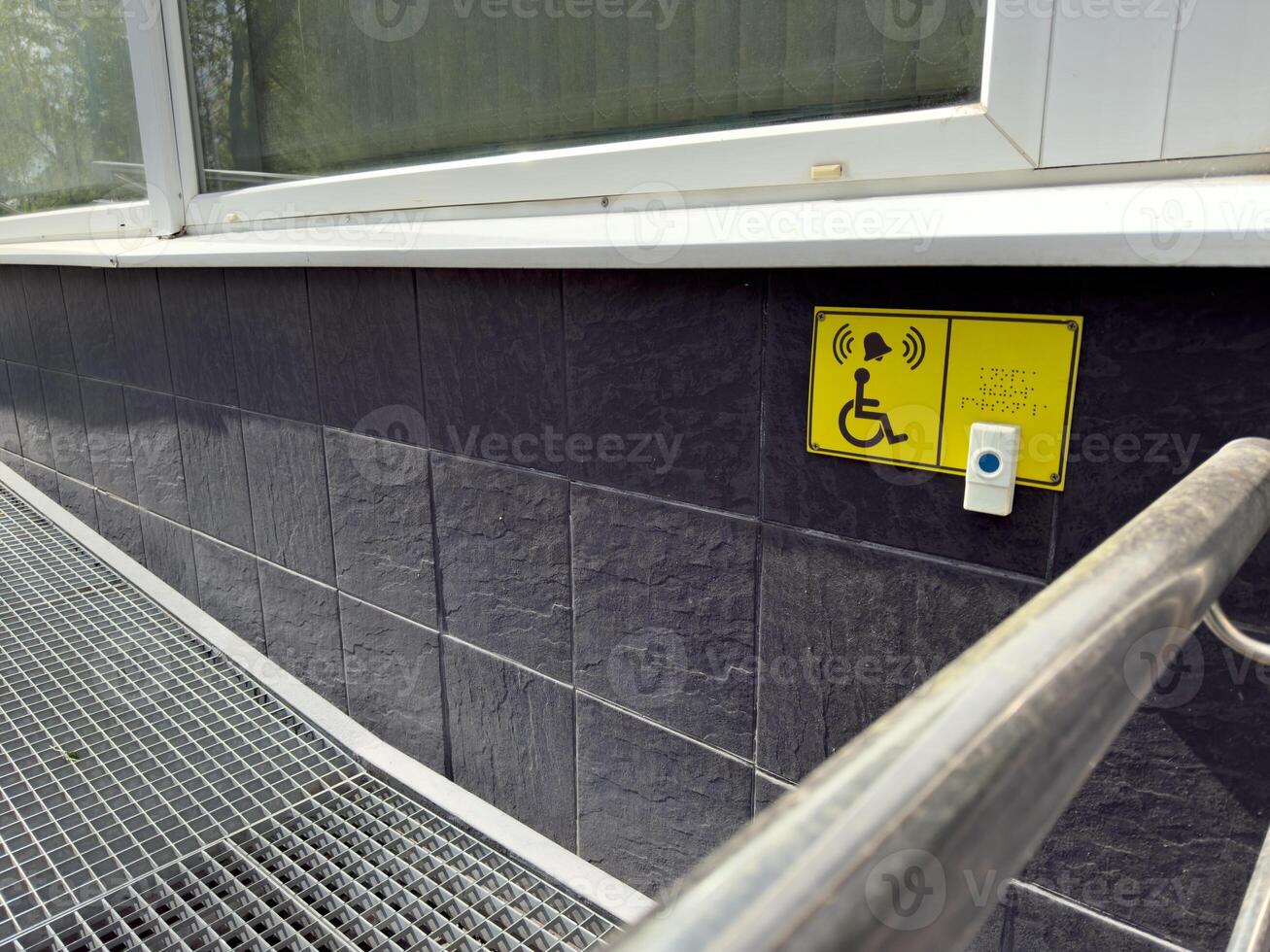 Barrier free access ramp with assistive call button and Braille signage, providing inclusive entry for wheelchair users and people with limited mobility in modern urban buildings photo