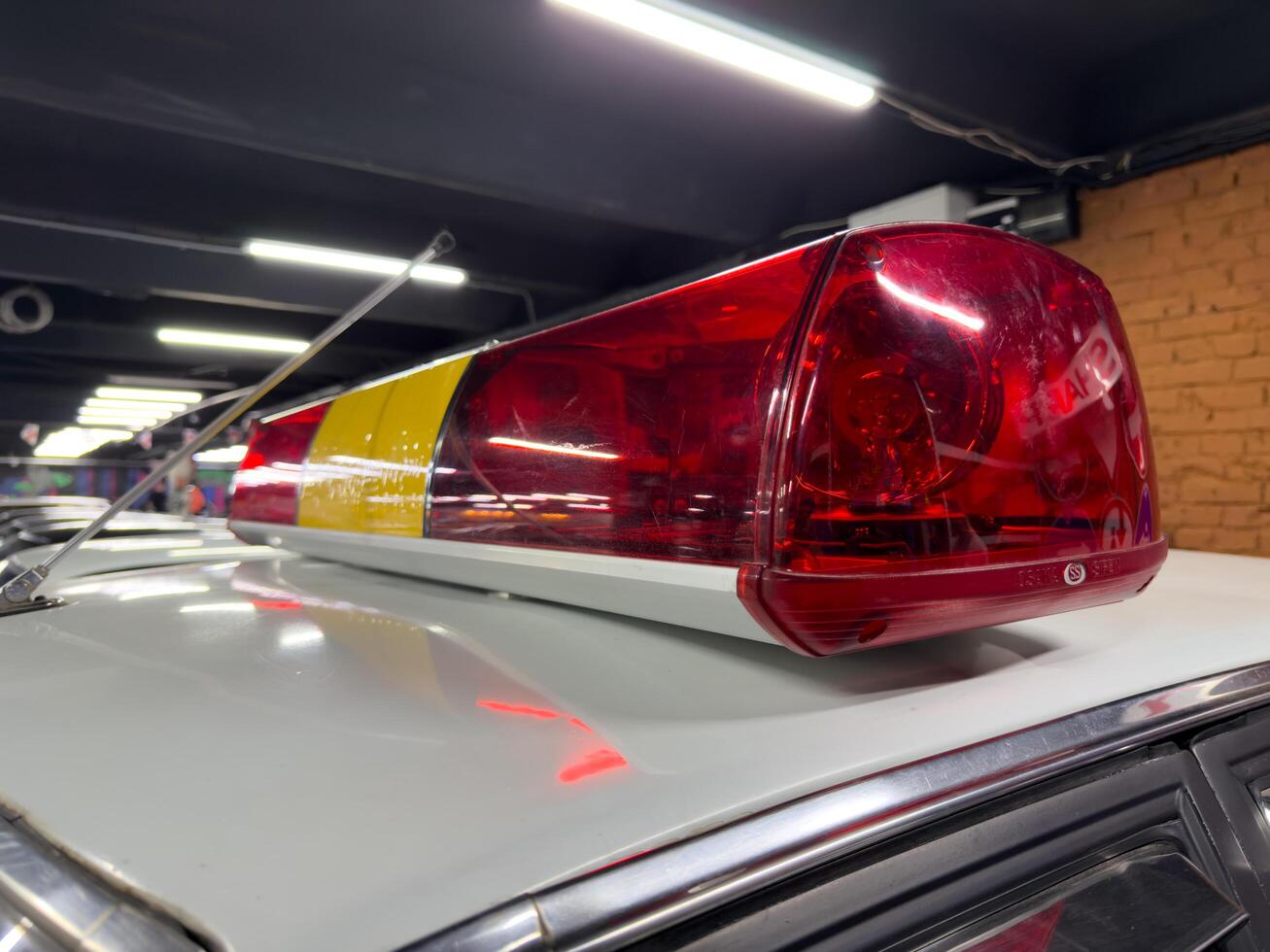Moscow, Russia, April 27, 2025 Low angle close up of red and yellow Osaka Siren emergency light bar mounted on a Japanese police car roof, showing contours and reflective highlights photo