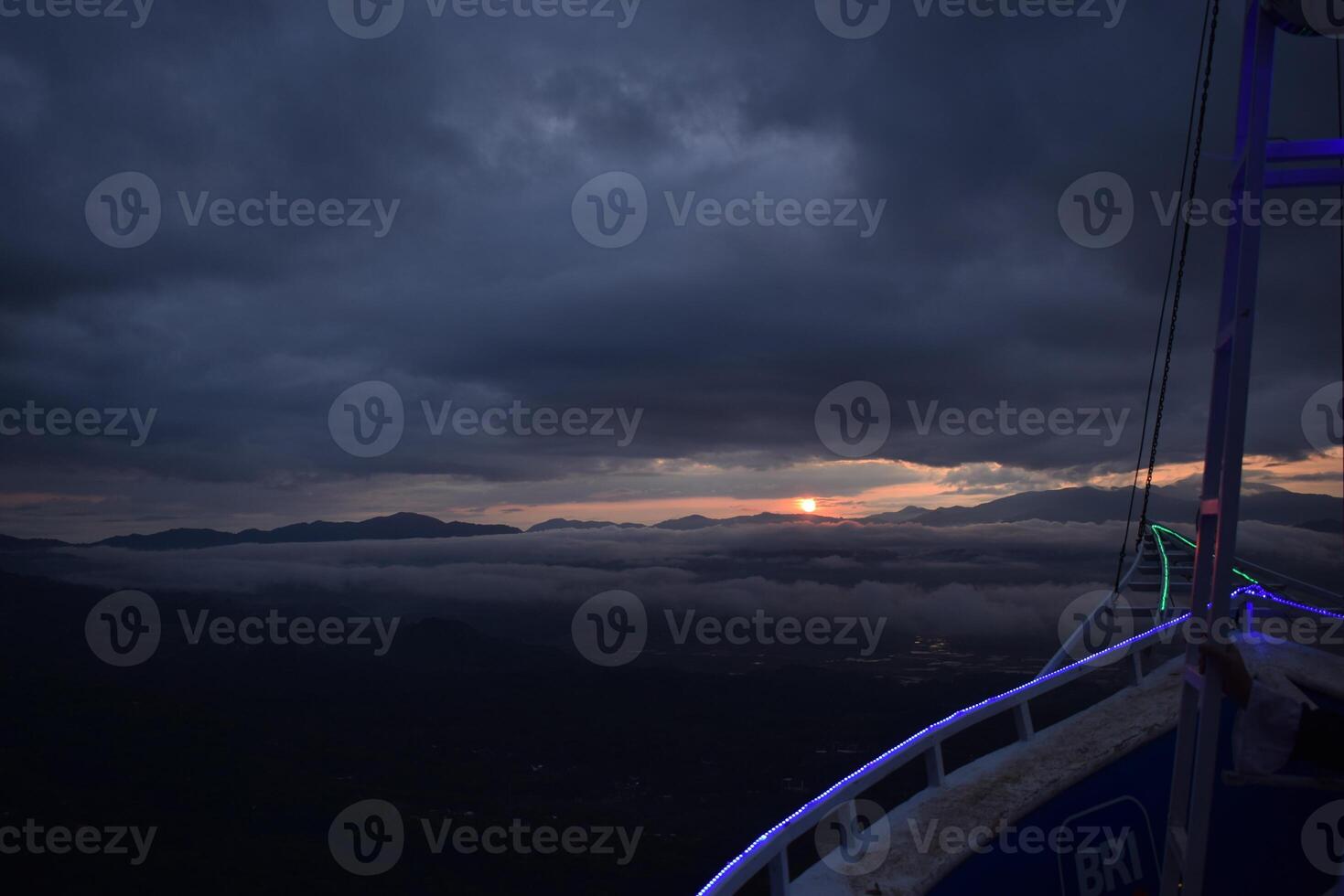A person sitting on a railing overlooking a valley photo