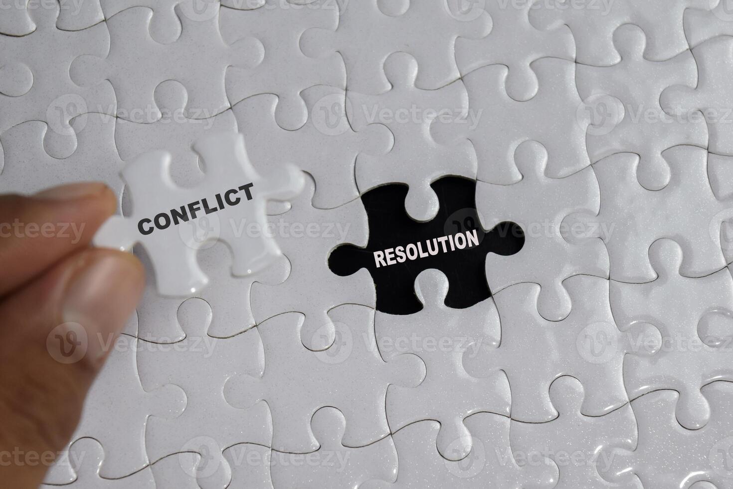 Hand holding piece of jigsaw puzzle with word Conflict resolution. Business and finance concept photo
