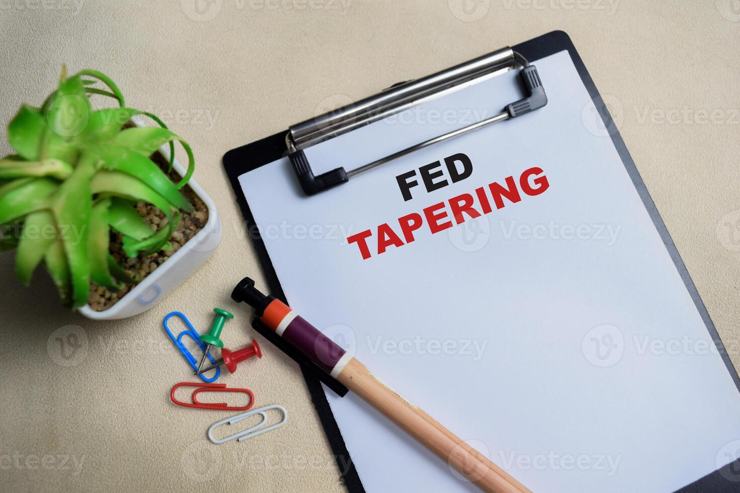 Concept of Fed tapering write on clipboard isolated on Wooden Table. photo