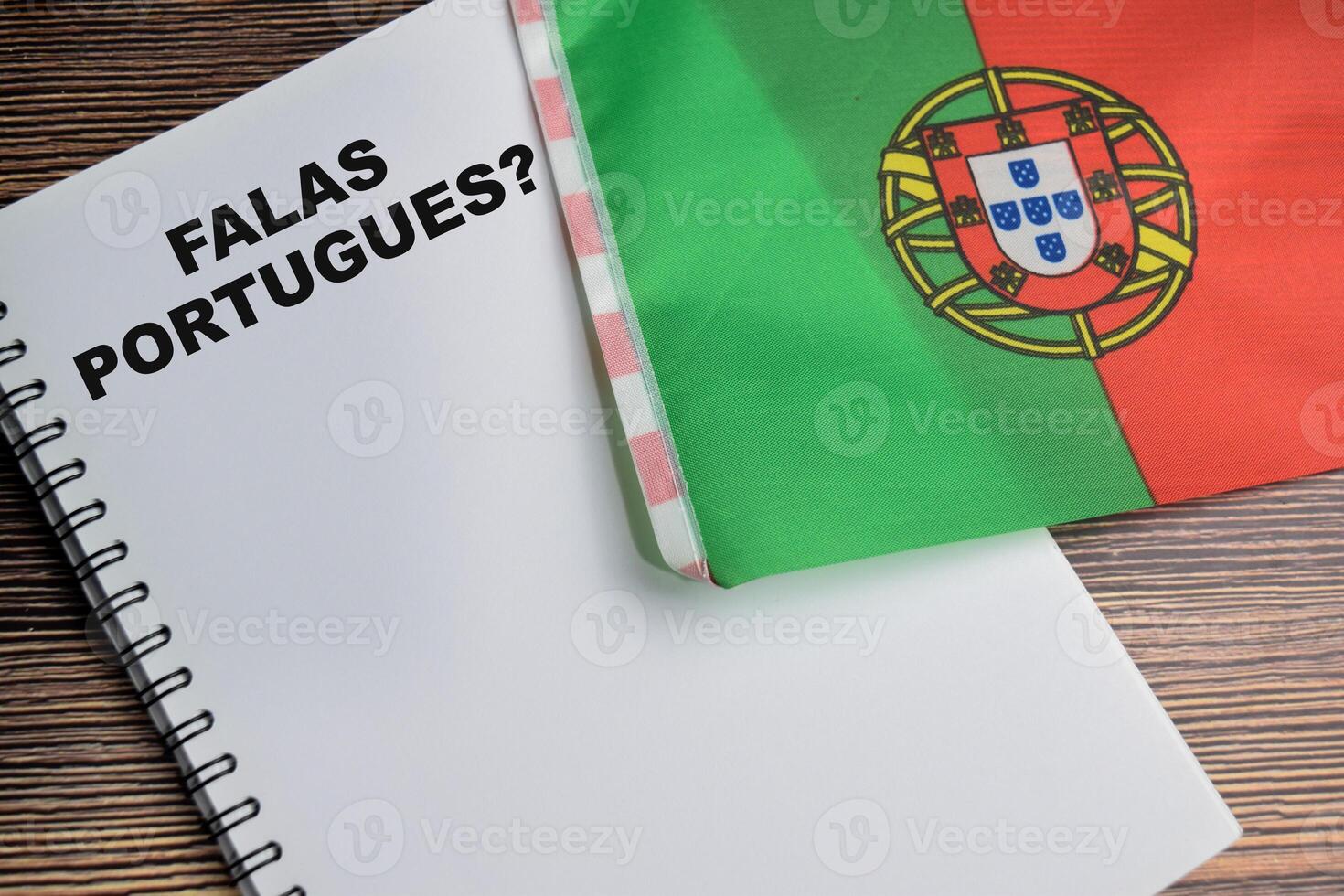 Concept of with question falas portugues write on book and flag of portugal isolated on Wooden Table. photo