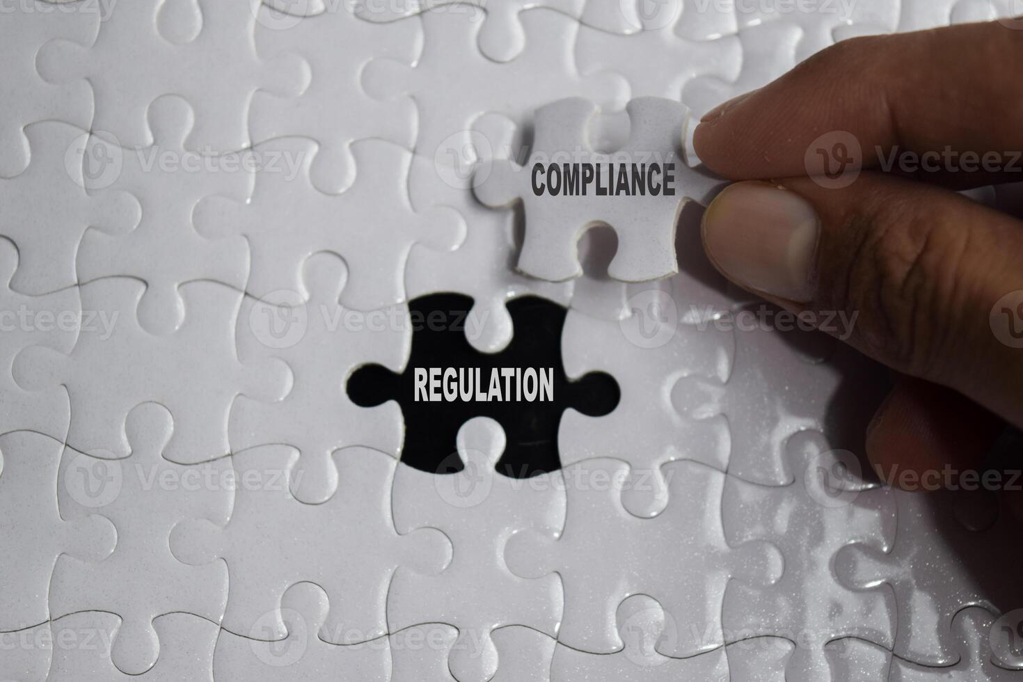 Hand holding piece of jigsaw puzzle with word Compliance regulation. Business and finance concept photo