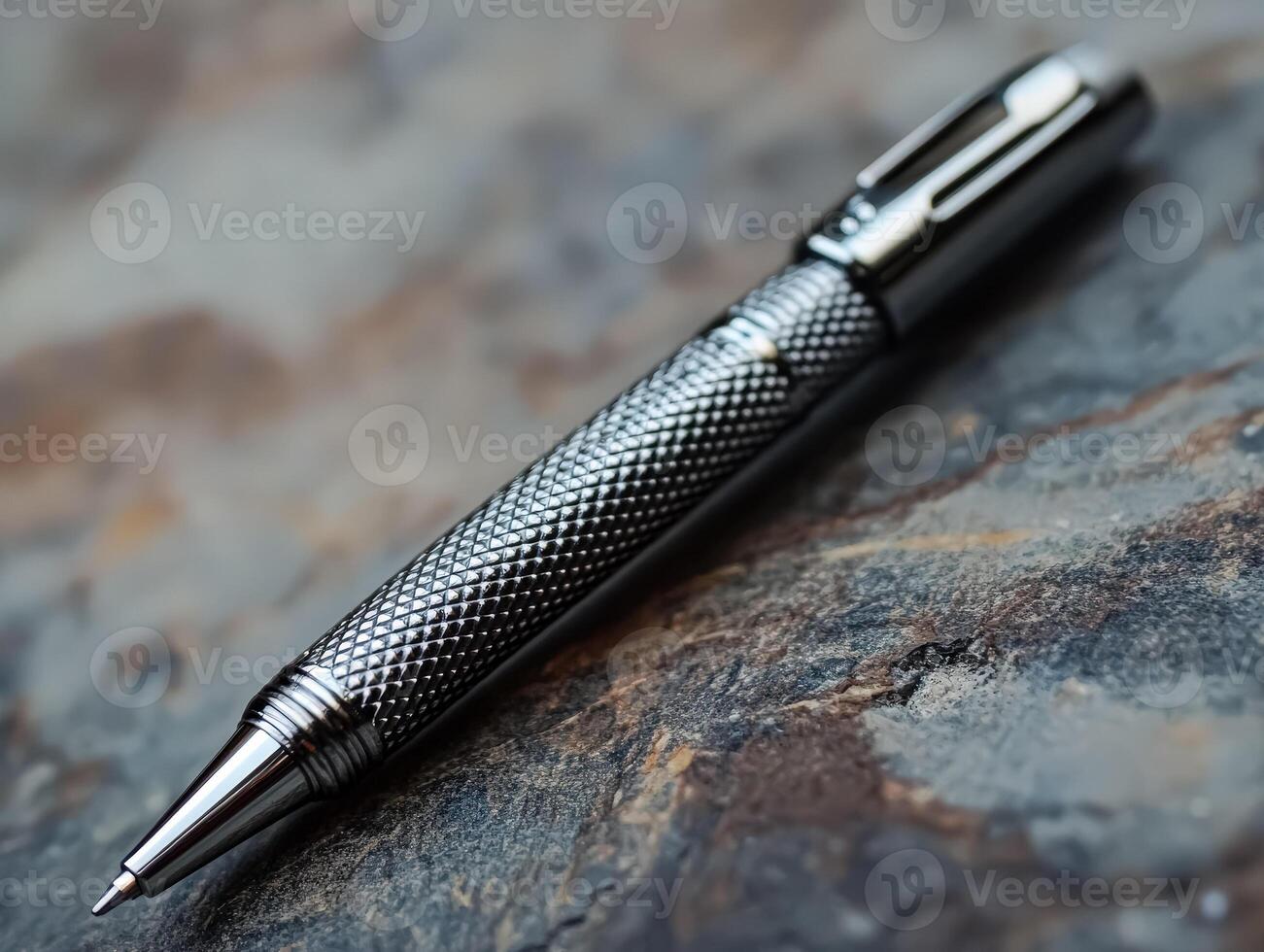 Pen with a black body and silver tip sits on a stone surface photo
