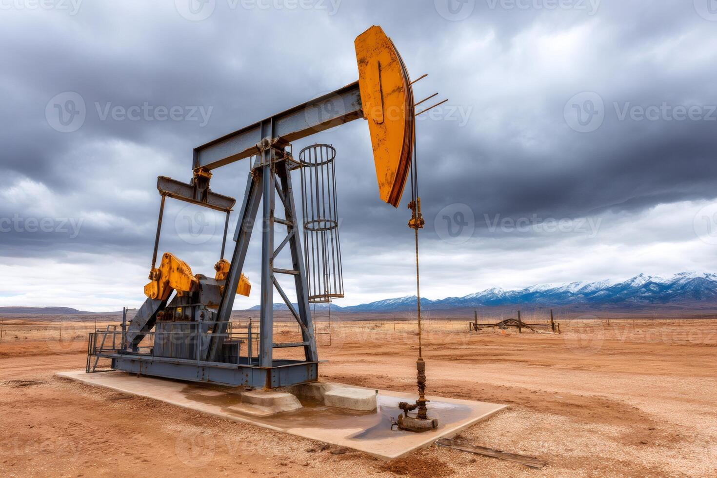 Pump jack extracting crude oil on a cloudy day with snowy mountains in background photo