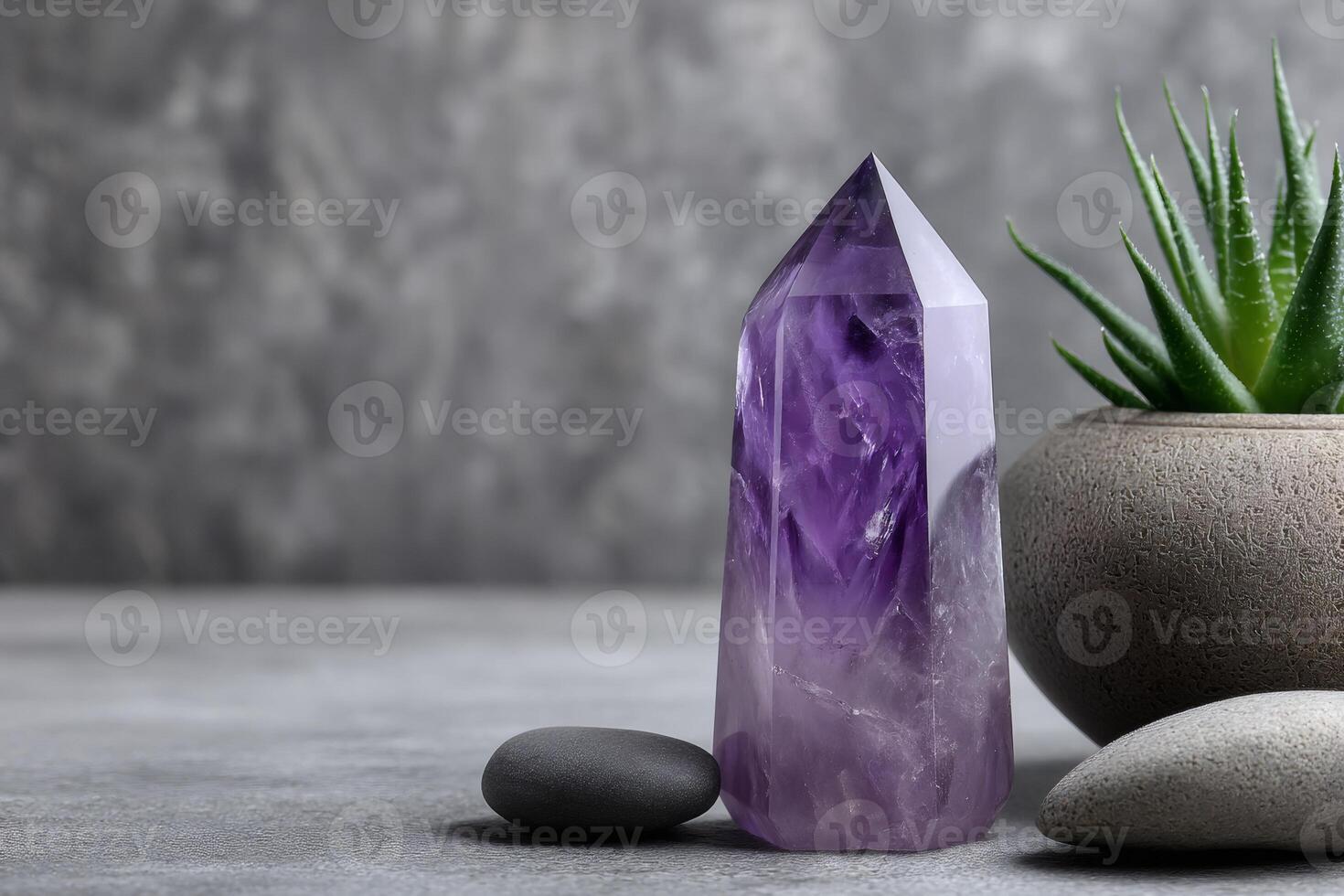 Beautiful amethyst crystal standing on gray surface with succulent plant photo