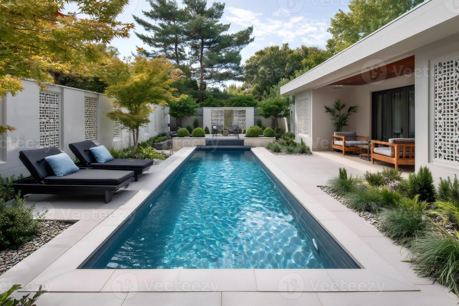 Modern backyard with swimming pool, deck chairs, and lush landscaping photo