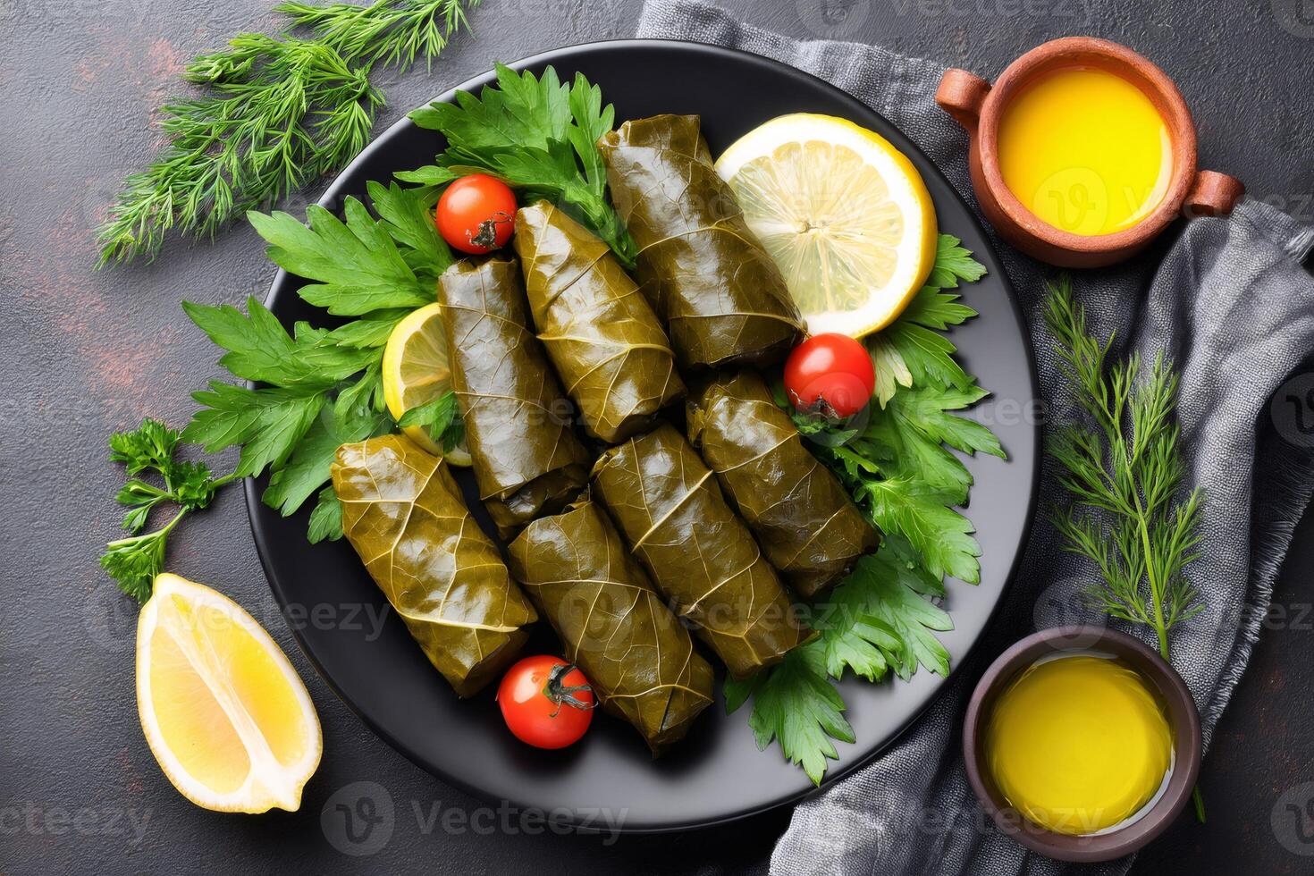Delicious dolma with lemon and herbs on black plate photo