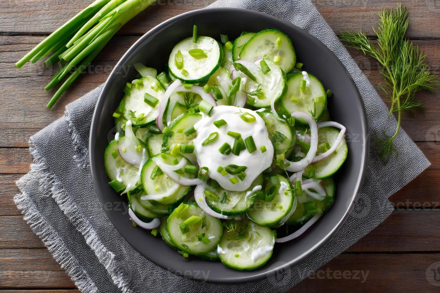 Cucumber salad with sour cream, red onion, chives and dill in a bowl photo