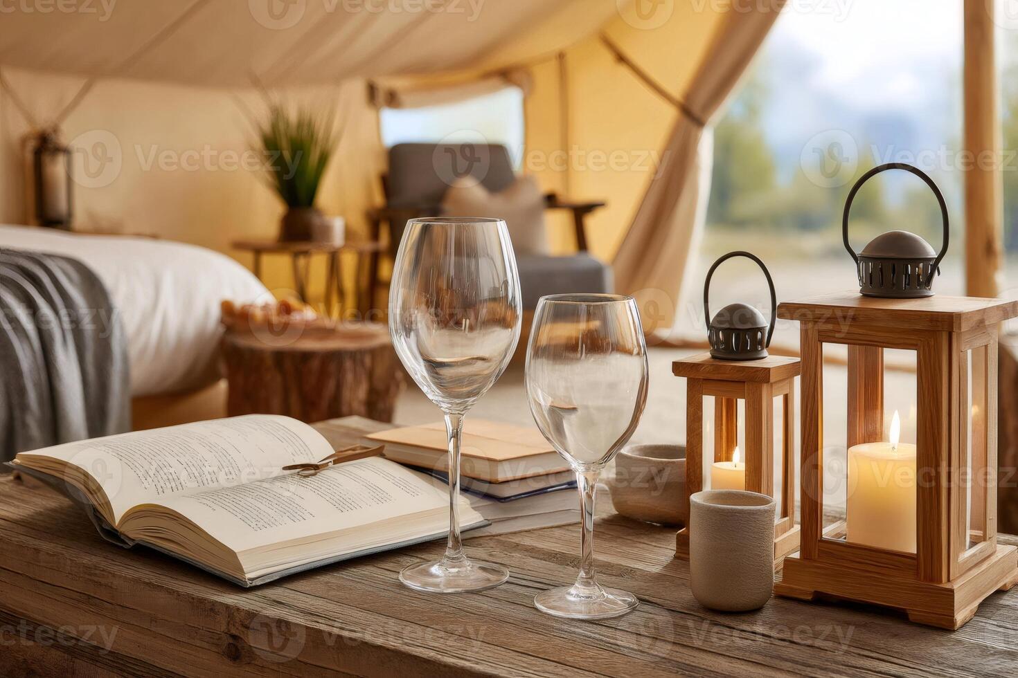 Wine glasses and book resting on table in cozy glamping tent photo