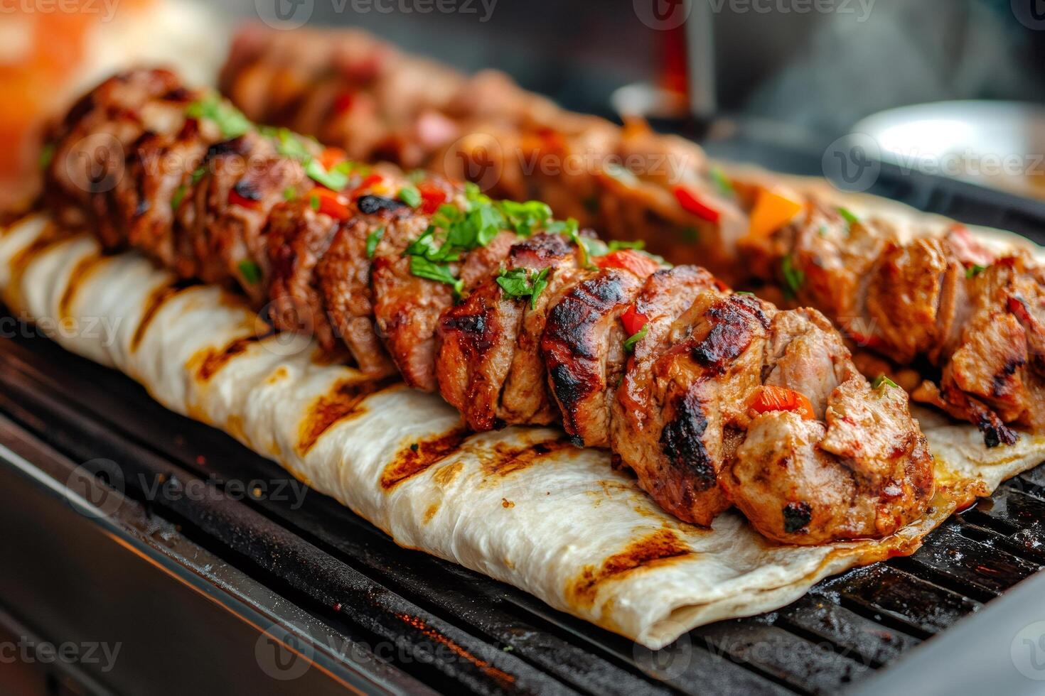Juicy pieces of meat with red pepper and herbs are grilling on pita bread photo