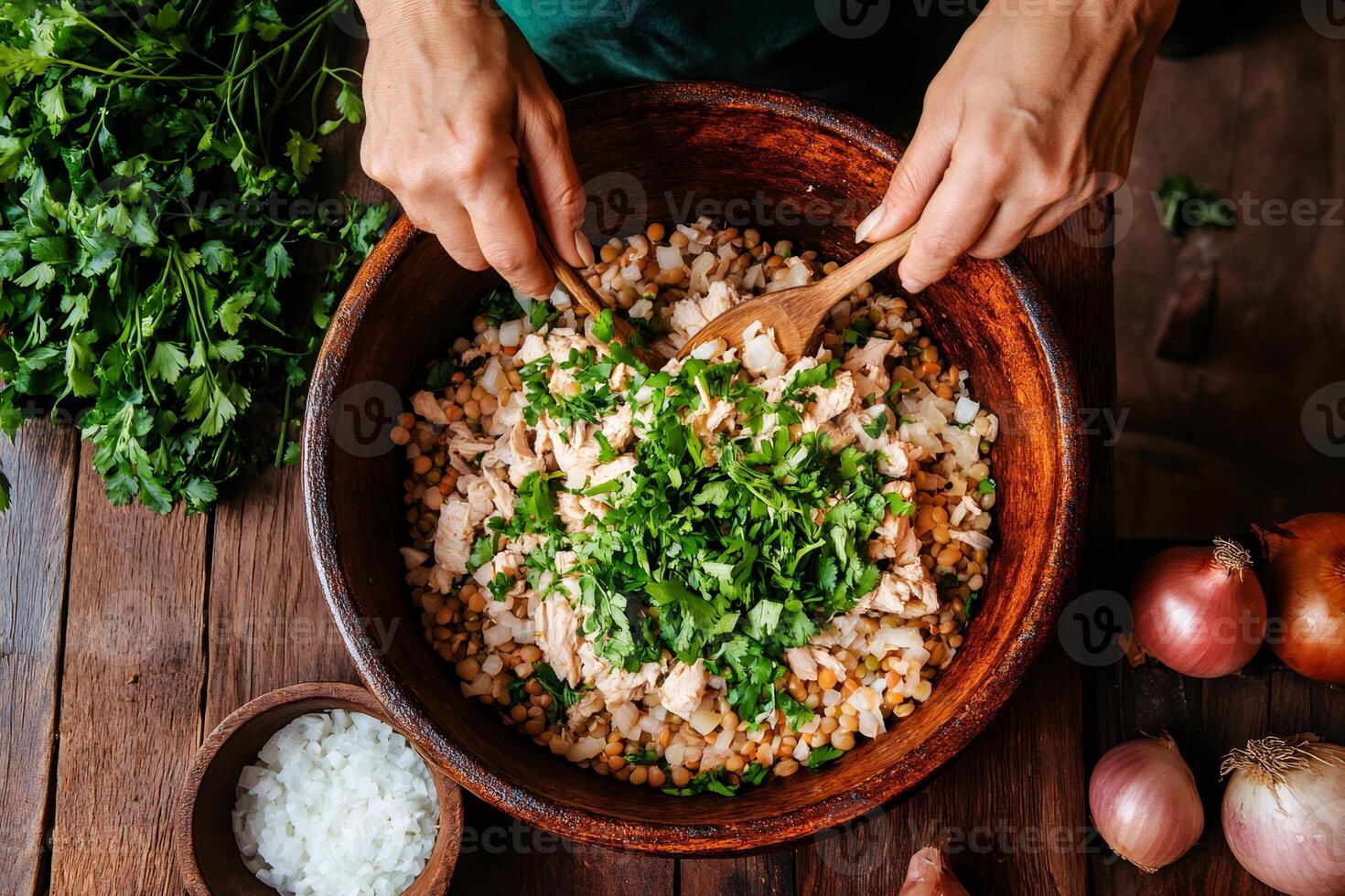 Chef mixing chicken, lentil, and parsley salad in wooden bowl photo