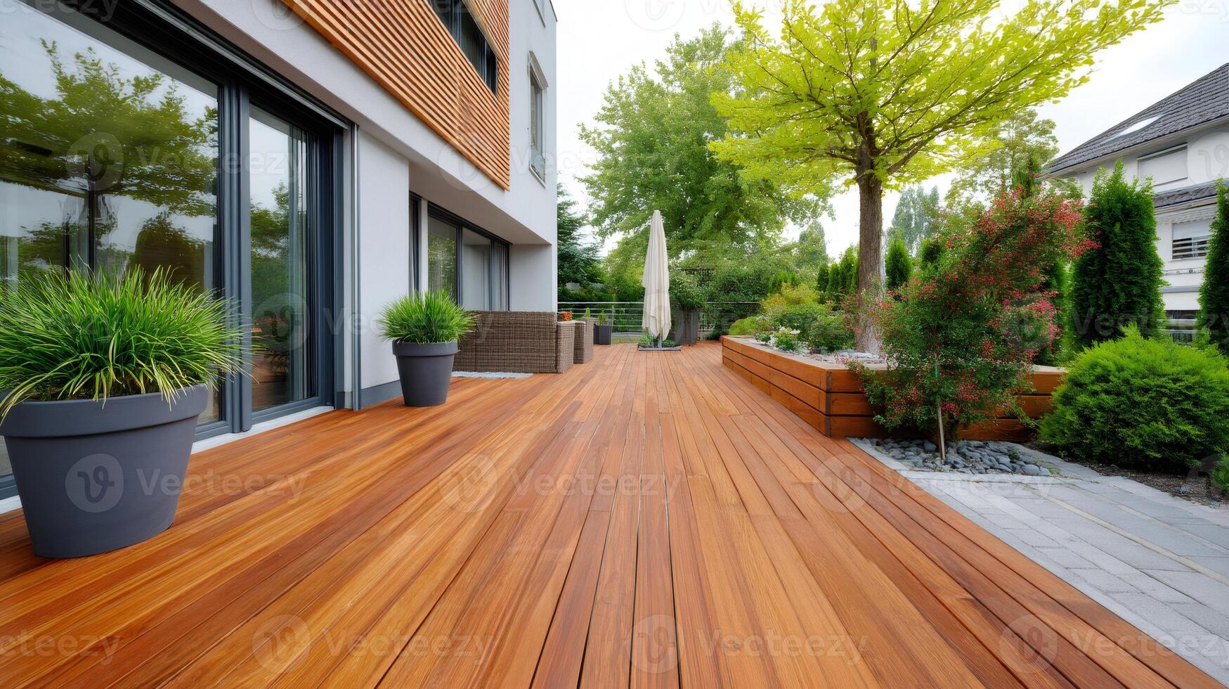Modern wooden terrace connecting house with garden during summer day photo