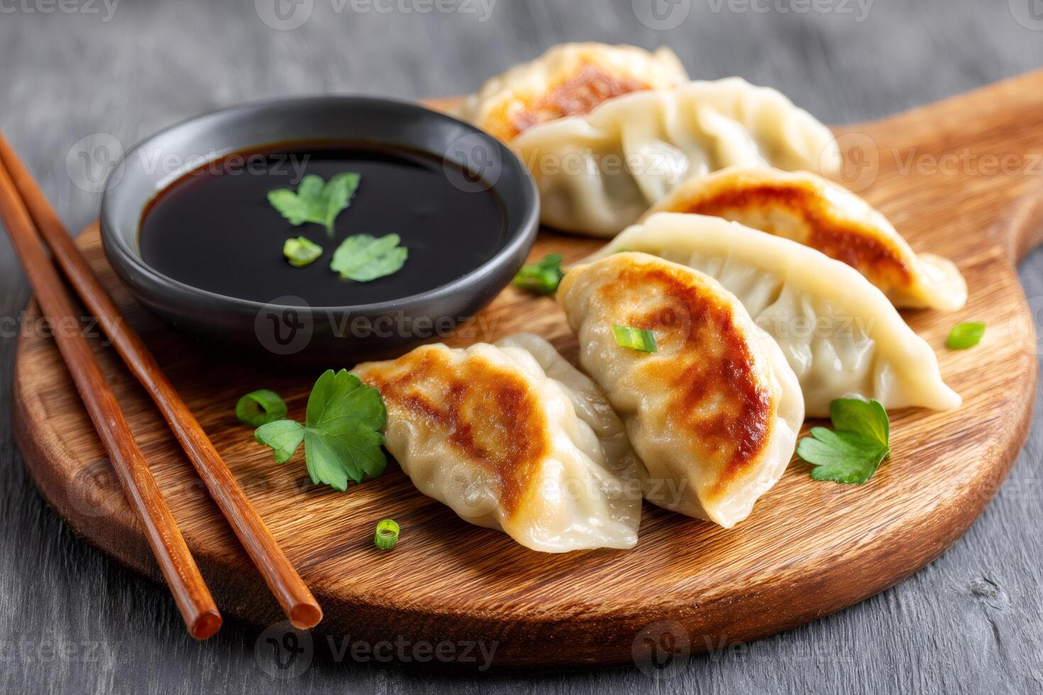 Fried gyoza dumplings served on wooden board with soy sauce and chopsticks photo