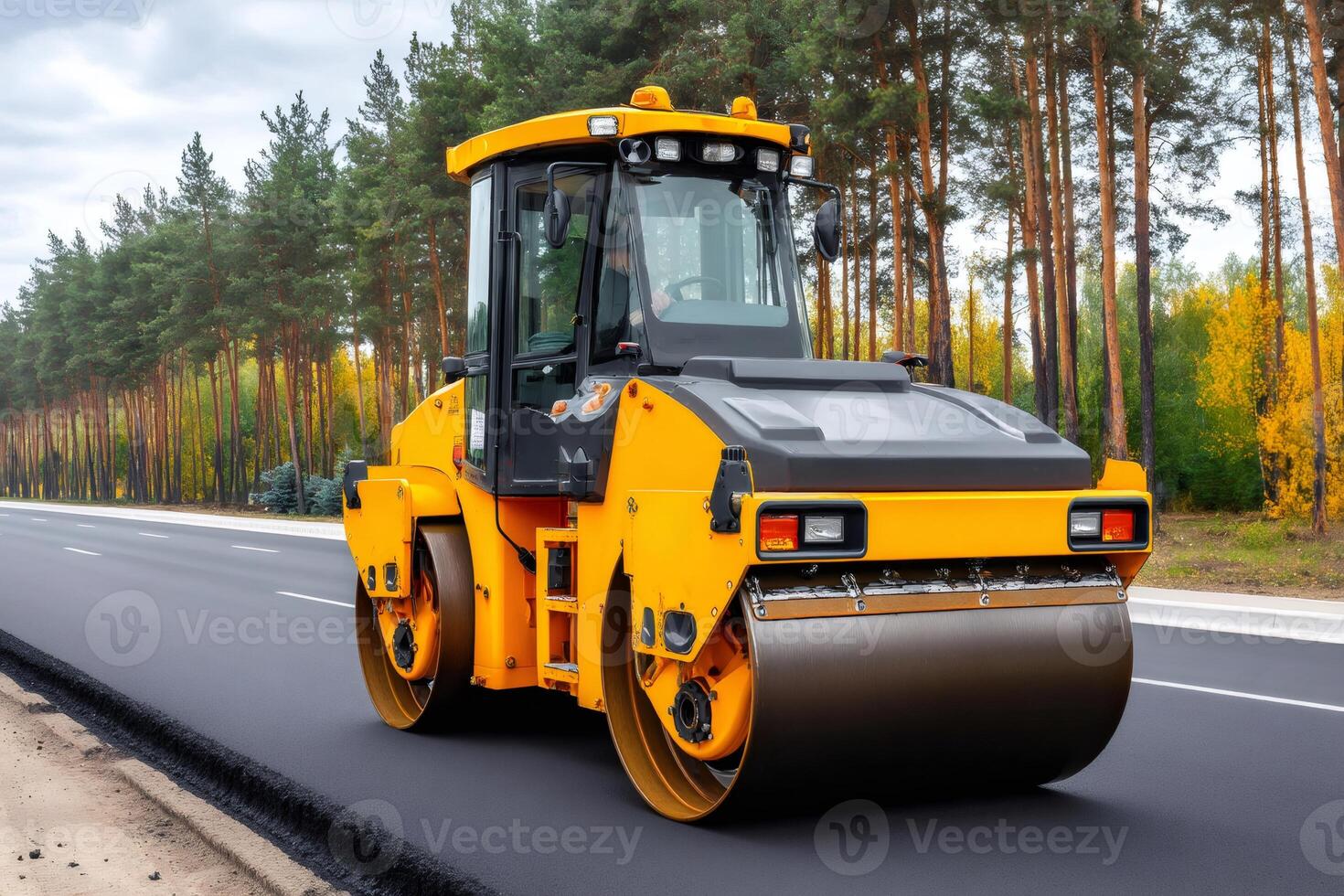 Heavy machinery working on a new road surrounded by autumn trees photo